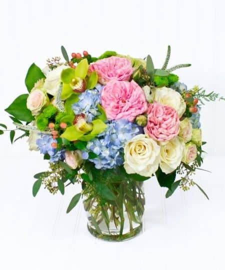 A lush arrangement of soft blues, greens, and creamy peaches designed with beautiful hydrangea, lavish roses, and striking orchids creates an arrangement perfect for any occasion. Overall arrangement is approx 18"H x 14"W and sits perfectly on a kitchen island or dining room table.