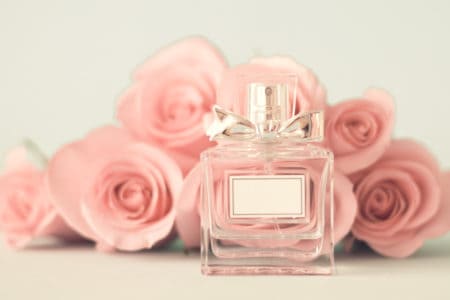 Perfume bottle in front of pink roses