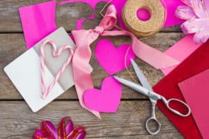 Pink paper, scissors, and twine for Valentine arts and crafts.